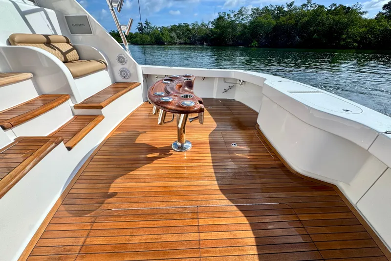 Slide: The Image of 2017 Viking 52 Sport Tower yacht with teak deck and seating, docked by lush greenery. - 13