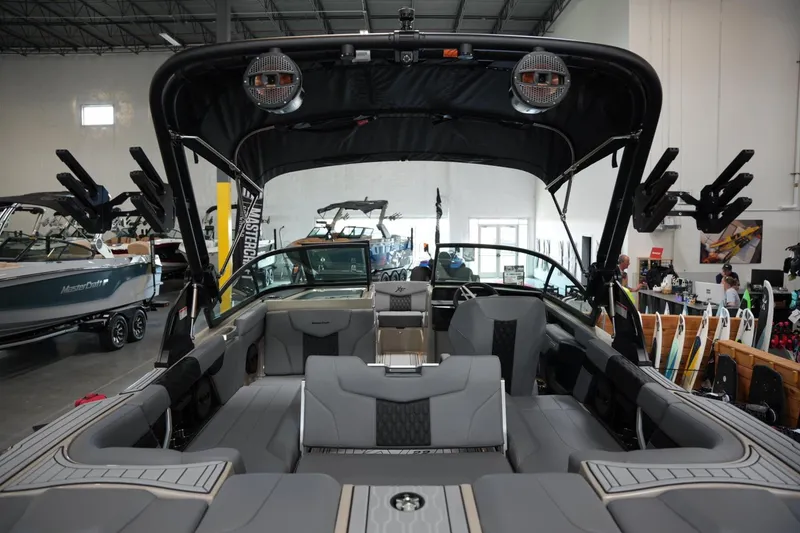 Slide: The Image of 2025 MasterCraft XT22 boat interior with sleek seating and advanced features in showroom. - 14