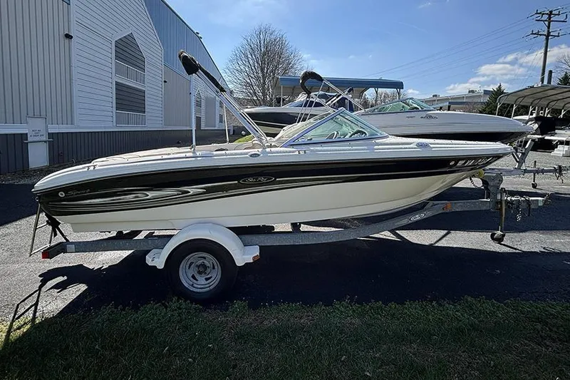 The Image of 2004 Sea Ray 185 Sport boat on trailer, parked outdoors near a building. - 0