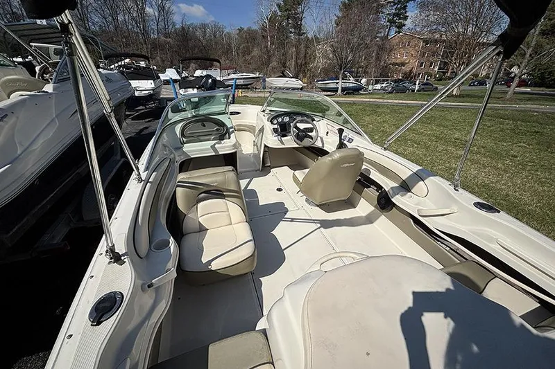 Slide: The Image of 2004 Sea Ray 185 Sport boat interior with seating and steering wheel, parked outdoors. - 6