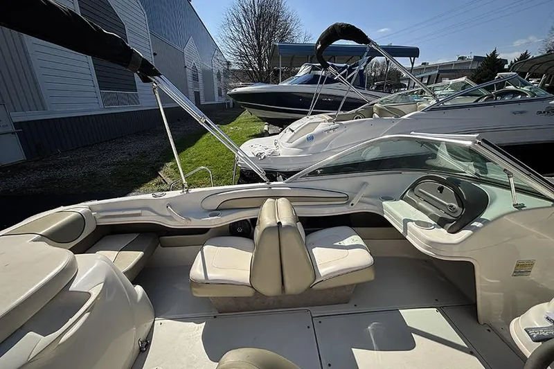 Slide: The Image of 2004 Sea Ray 185 Sport boat interior with seating and steering wheel, parked outdoors. - 9