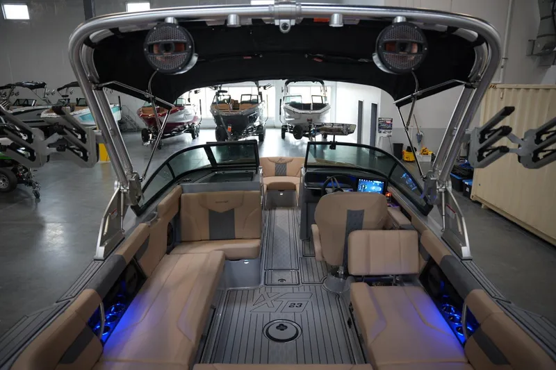 Slide: The Image of 2025 MasterCraft XT23 boat interior with modern seating and dashboard in a showroom. - 14