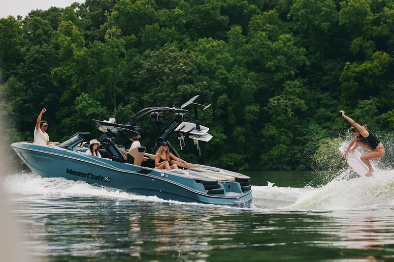 Slide: The Image of Manufacturer Provided Image: 2025 MasterCraft XT23 boat with people enjoying wakeboarding on a scenic lake. - 19