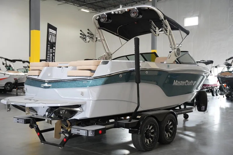 Slide: The Image of 2025 MasterCraft XT23 boat on trailer in showroom, rear view. - 2