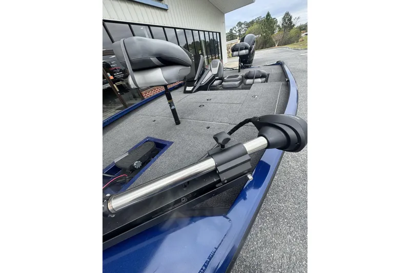 Slide: The Image of 2024 Lowe Stinger 175C fishing boat with seating and trolling motor, parked outdoors. - 11