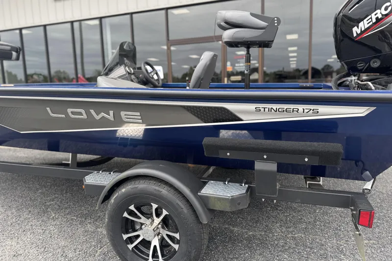 Slide: The Image of 2024 Lowe Stinger 175C boat, blue exterior, parked on a trailer outside a building. - 2