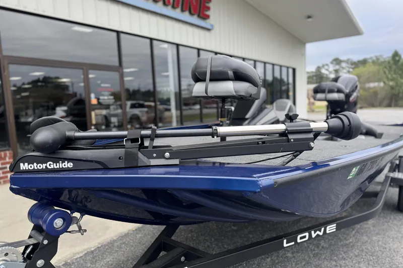 Slide: The Image of 2024 Lowe Stinger 175C boat with MotorGuide trolling motor, parked outside a showroom. - 5