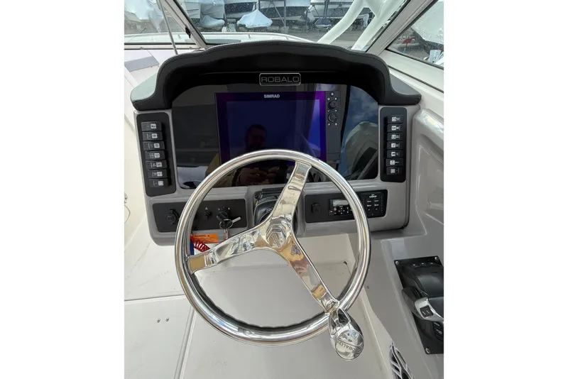 Slide: The Image of 2021 Robalo R247 Dual Console helm with steering wheel and Simrad display. - 7