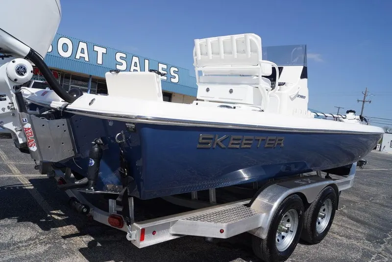 Slide: The Image of 2026 Skeeter SX241 boat on trailer at dealership under clear blue sky. - 5