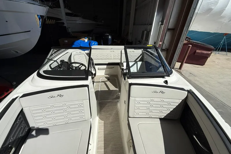 Slide: The Image of 2025 Sea Ray 19 SPX OB boat interior with seating and steering wheel in a garage. - 8