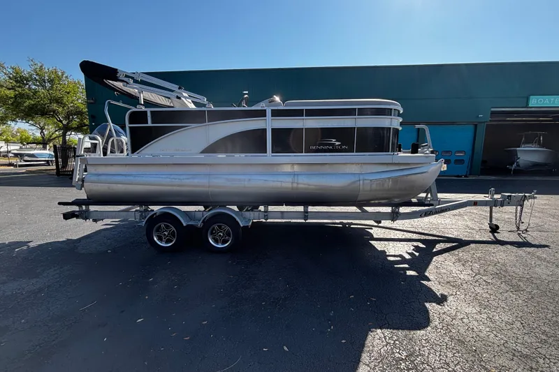 The Image of 2023 Bennington 188SLJ pontoon boat on trailer, parked outdoors. - 1