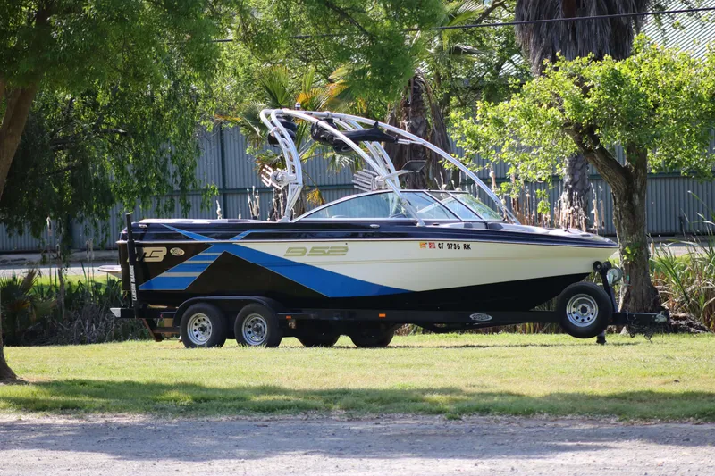 The Image of 2012 MB B-52 23 Widebody boat on trailer, parked on grass with trees in background. - 1