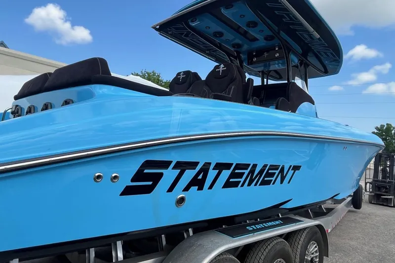 Slide: The Image of 2025 Statement 350 Open boat in vibrant blue on a trailer, under a clear sky. - 11