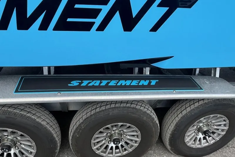 Slide: The Image of Trailer with "Statement" branding, featuring wheels and blue design, 2025 Statement 350 Open. - 13