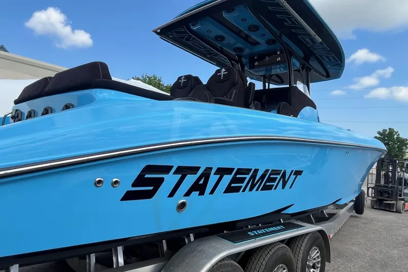 Slide: The Image of 2025 Statement 350 Open boat in vibrant blue on trailer, under clear sky. - 7