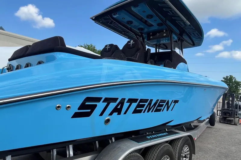 Slide: The Image of 2025 Statement 350 Open boat in vibrant blue on a trailer, under a clear sky. - 8