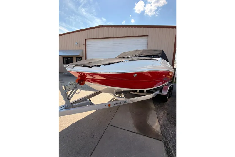 Slide: The Image of 2023 Stingray 201 DC boat on calm water near waterfront homes. - 2