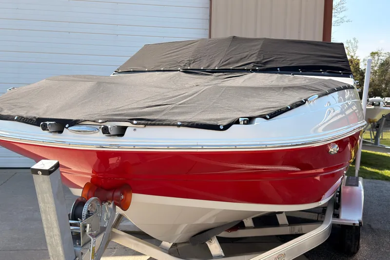 Slide: The Image of 2023 Stingray 201 DC boat with red hull on calm water under clear blue sky. - 3