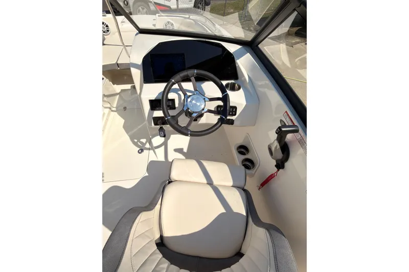 Slide: The Image of 2023 Stingray 201 DC boat on trailer, red and white, parked outside a garage. - 8