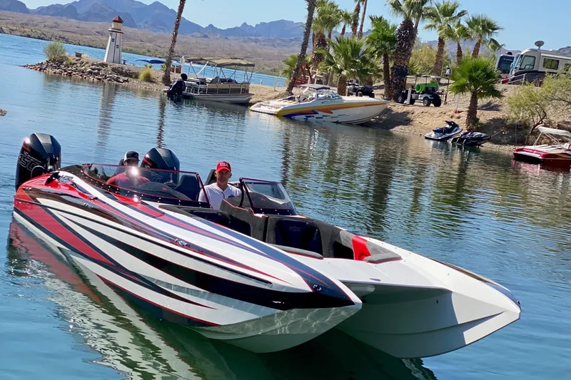 Slide: The Image of 2021 Daves Custom Boats M-28R on a scenic lake with palm trees and mountains. - 2