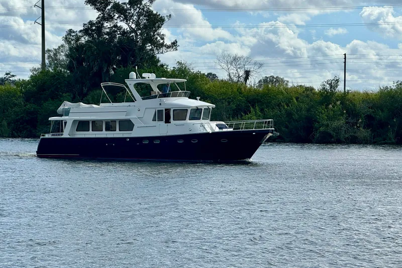 Slide: The Image of 2005 Jefferson Pilothouse 63 yacht cruising on a calm river under a cloudy sky. - 2