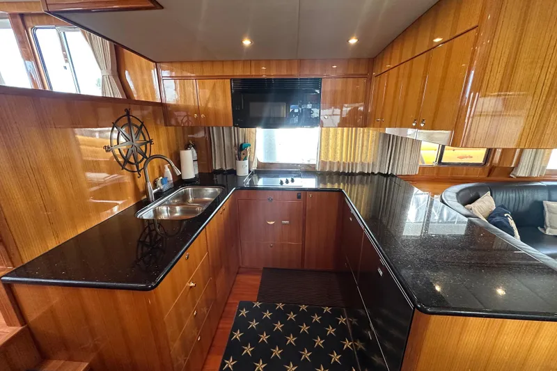 Slide: The Image of Luxurious kitchen interior of 2005 Jefferson Pilothouse 63 yacht with wood cabinetry and black countertops. - 23