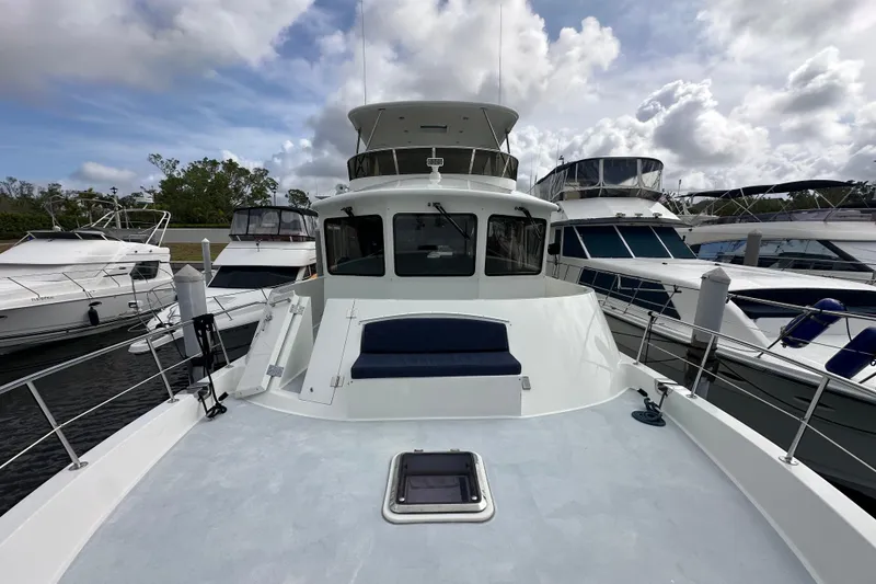 Slide: The Image of 2005 Jefferson Pilothouse 63 yacht docked among other boats under a cloudy sky. - 4