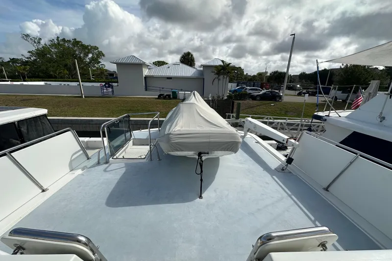 Slide: The Image of 2005 Jefferson Pilothouse 63 yacht deck with covered equipment, docked near greenery and buildings. - 6
