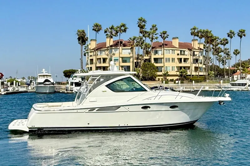 Slide: The Image of 2007 Tiara Yachts 3000 Open cruising near waterfront buildings and palm trees. - 2