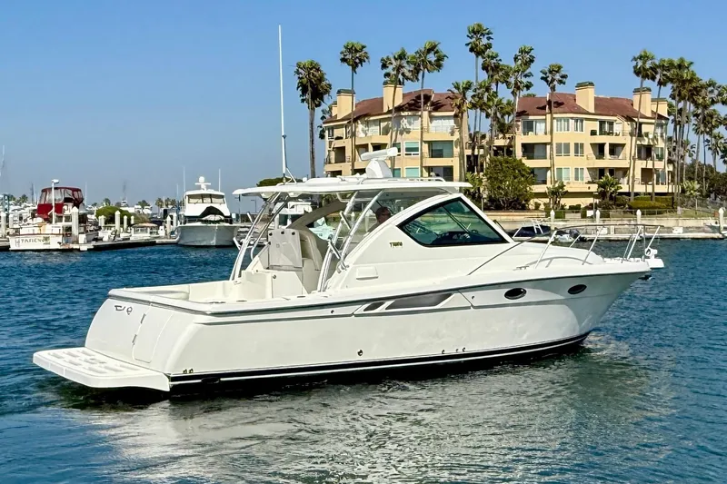 Slide: The Image of 2007 Tiara Yachts 3000 Open cruising in a marina with palm trees and buildings. - 3