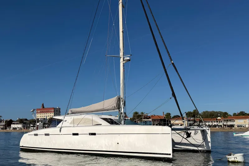Slide: The Image of 2009 Nautitech 47 catamaran sailing near coastal buildings under clear blue sky. - 10