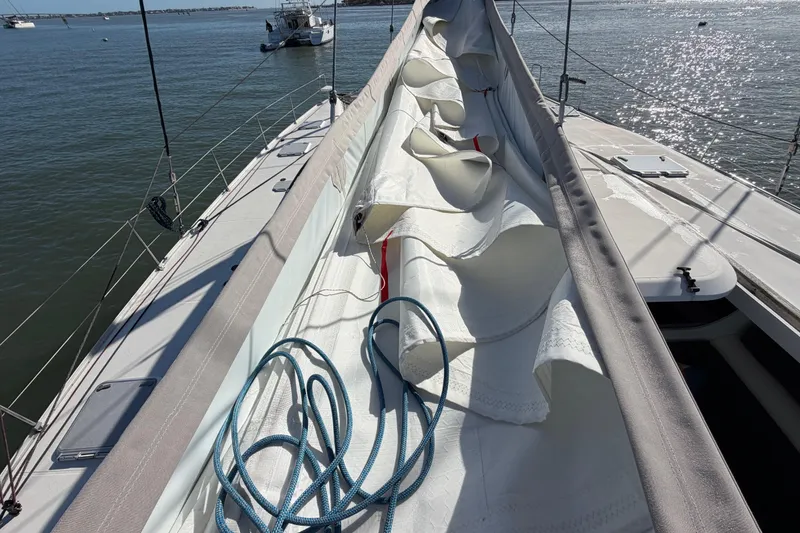 Slide: The Image of 2009 Nautitech 47 sailboat deck with sails and ropes, anchored on calm water. - 109