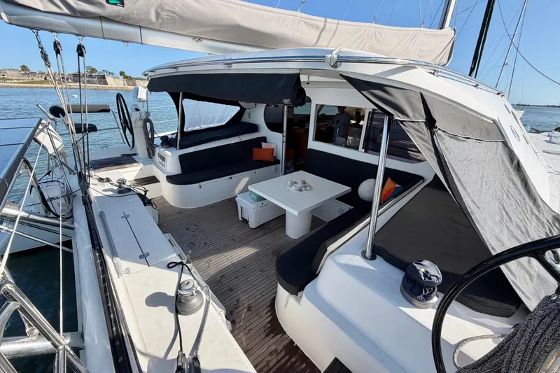 Slide: The Image of Spacious deck of 2009 Nautitech 47 catamaran with seating and table, docked by the water. - 17