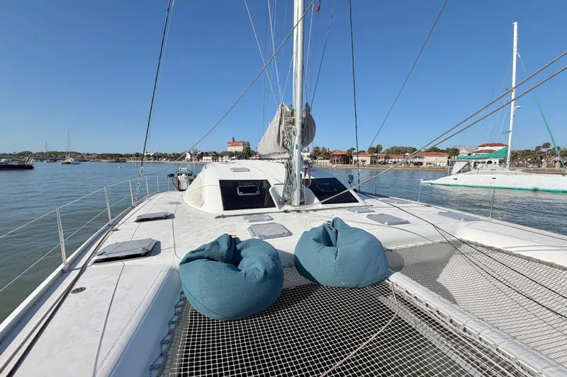Slide: The Image of 2009 Nautitech 47 catamaran with bean bags on deck, docked in a serene harbor. - 21