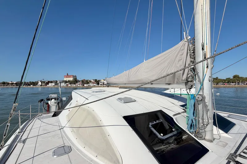 Slide: The Image of Sailing yacht Nautitech 47, 2009 model, docked near a coastal town under clear blue skies. - 24