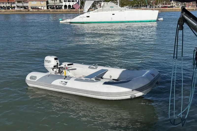Slide: The Image of Inflatable boat with Suzuki motor on water, Nautitech 47 catamaran in background, 2009 model. - 96