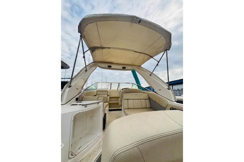 Slide: The Image of 2019 Regal 28 Express boat interior with canopy, featuring beige seating and open storage. - 10