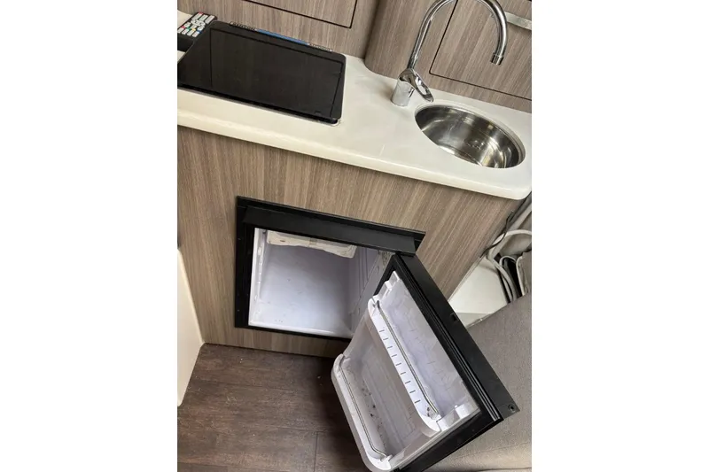 Slide: The Image of Compact kitchenette in 2019 Regal 28 Express boat with sink and open mini fridge. - 21