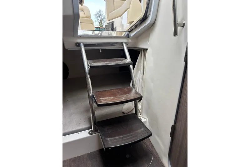 Slide: The Image of Interior stairs of a 2019 Regal 28 Express boat, featuring wooden steps and metal railing. - 29