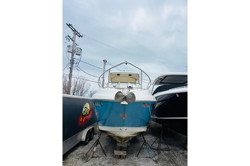 Slide: The Image of 2019 Regal 28 Express boat on stands, blue hull, overcast sky background. - 43
