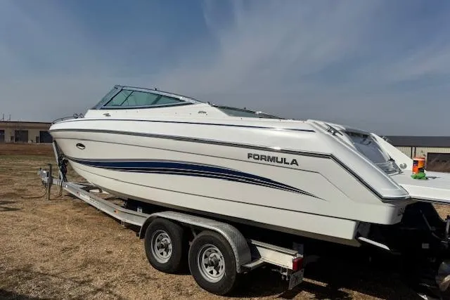 Slide: The Image of 2007 Formula 280 Bowrider boat on trailer, white with blue accents, parked outdoors. - 4