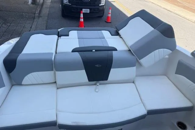 Slide: The Image of 2023 Chaparral 21 SSi boat with gray and white seating, parked near traffic cones. - 23