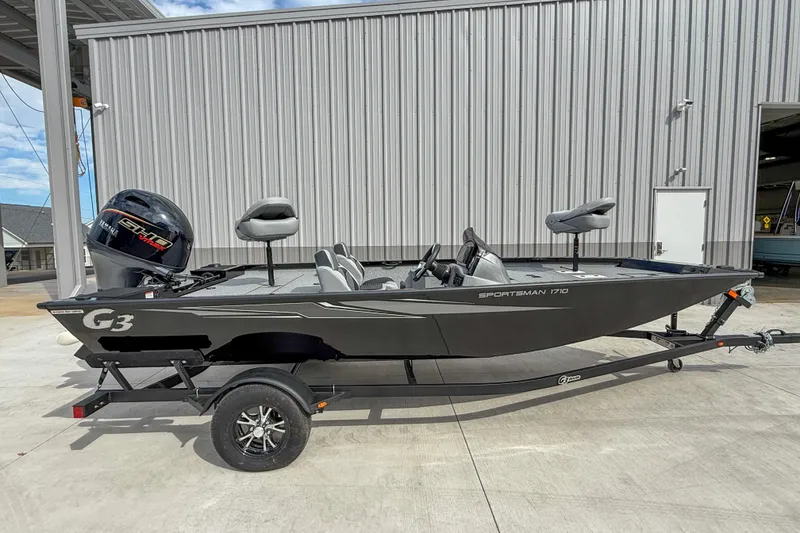 The Image of 2026 G3 Sportsman 1710 boat on trailer, parked outdoors near a metal building. - 1
