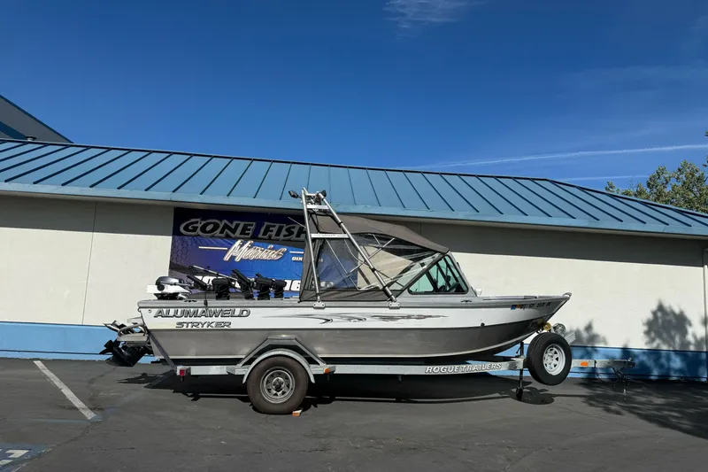 The Image of 2006 Alumaweld Stryker Sport 19 boat on trailer, parked outside a building under clear blue sky. - 1