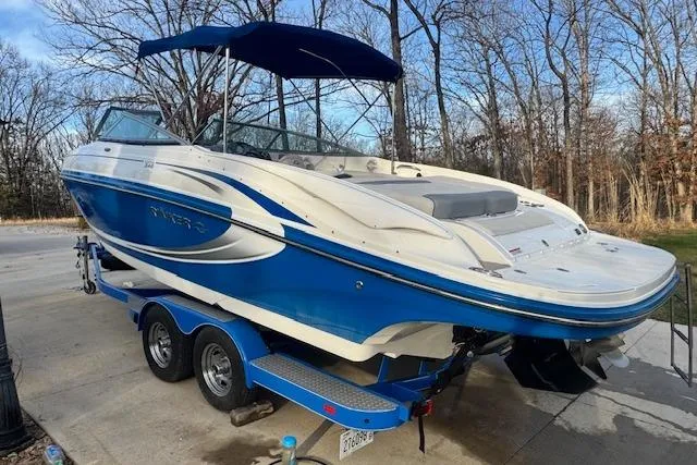 Slide: The Image of 2013 Rinker 246 Captiva Bowrider on trailer, blue and white, parked outdoors. - 10