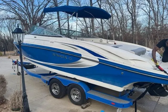 Slide: The Image of 2013 Rinker 246 Captiva Bowrider boat on trailer, blue and white, parked outdoors. - 2