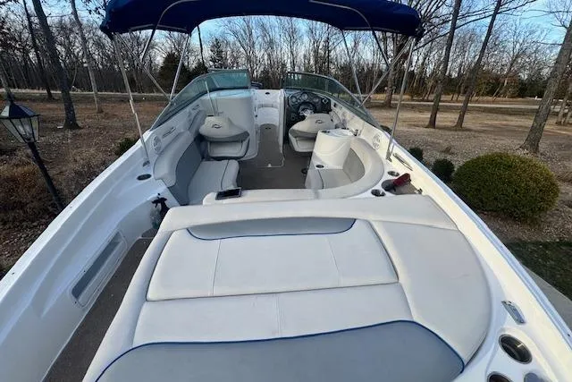 Slide: The Image of 2013 Rinker 246 Captiva Bowrider with spacious seating and canopy in a wooded area. - 28