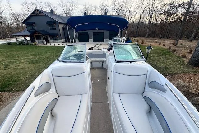 Slide: The Image of 2013 Rinker 246 Captiva Bowrider with white seating, parked near a modern house. - 30