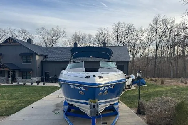 Slide: The Image of 2013 Rinker 246 Captiva Bowrider on trailer in front of modern house. - 4
