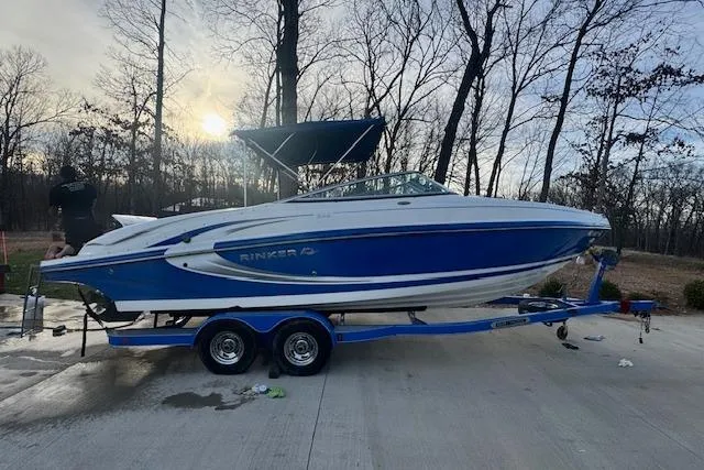 Slide: The Image of 2013 Rinker 246 Captiva Bowrider on trailer, blue and white, parked outdoors. - 5